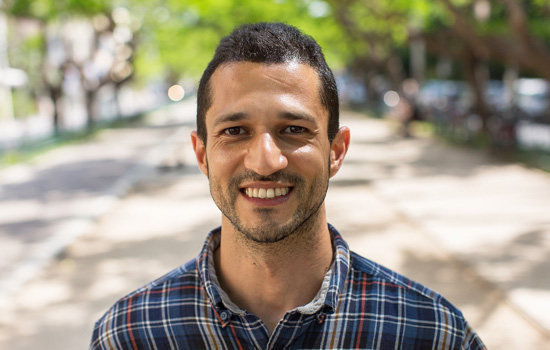Karim smiling at the camera in an outdoor setting