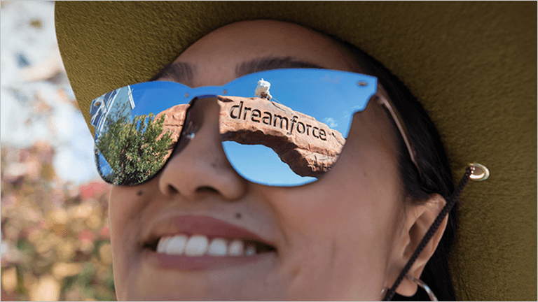 Woman wearing mirrored sunglasses, with the Dreamforce arch reflected in the lens