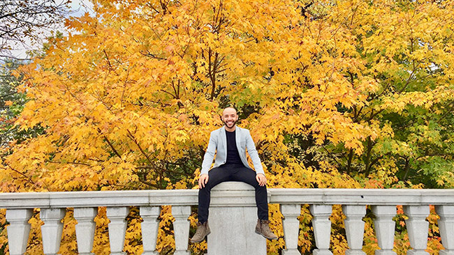 Johnny Silva sitting on a fence in the fall